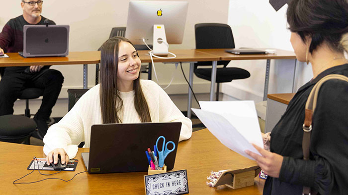 An IT student employee assists a customer at the service desk