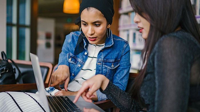 Two SDSU students look over a laptop